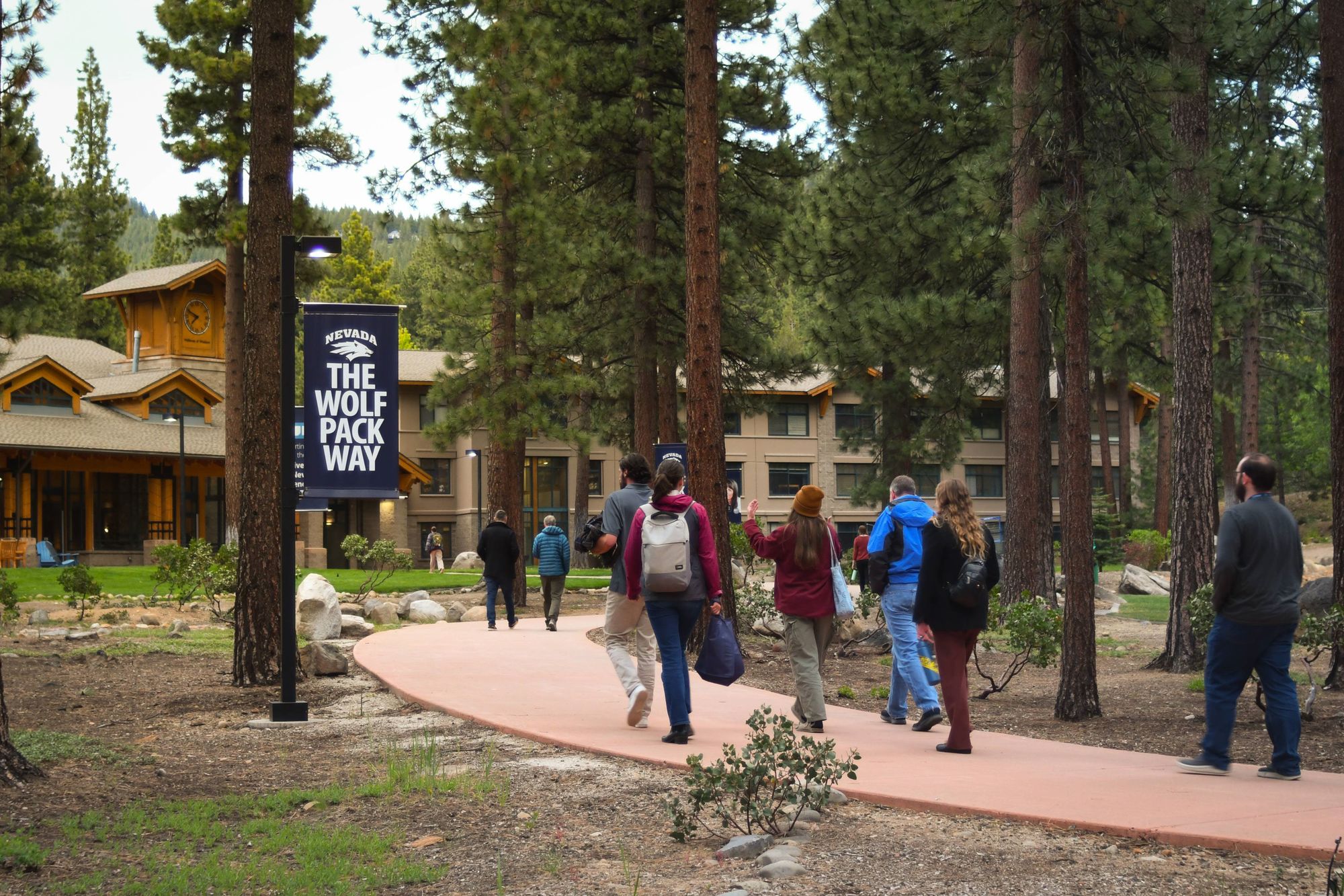 Students walking a forest path on the University of Nevada, Reno at Lake Tahoe campus beneath a Wolf Pack Way banner