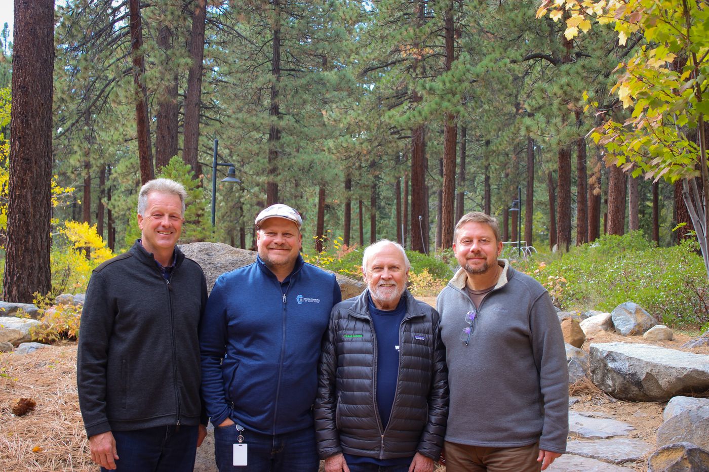 Scott Chadwick, Christopher Jeffrey, Mick Hitchcock and Dmitry Koltun standing together in a pine forest
